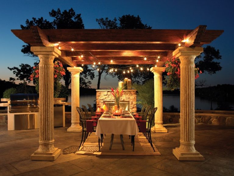 A table and chairs under an arbor at night.