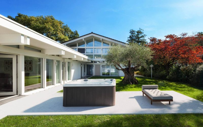 A large outdoor spa sits in the middle of an outside patio. A large outdoor spa sits in the middle of an outside patio.