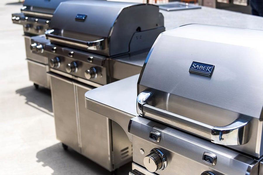 A row of barbecues are lined up on the floor.